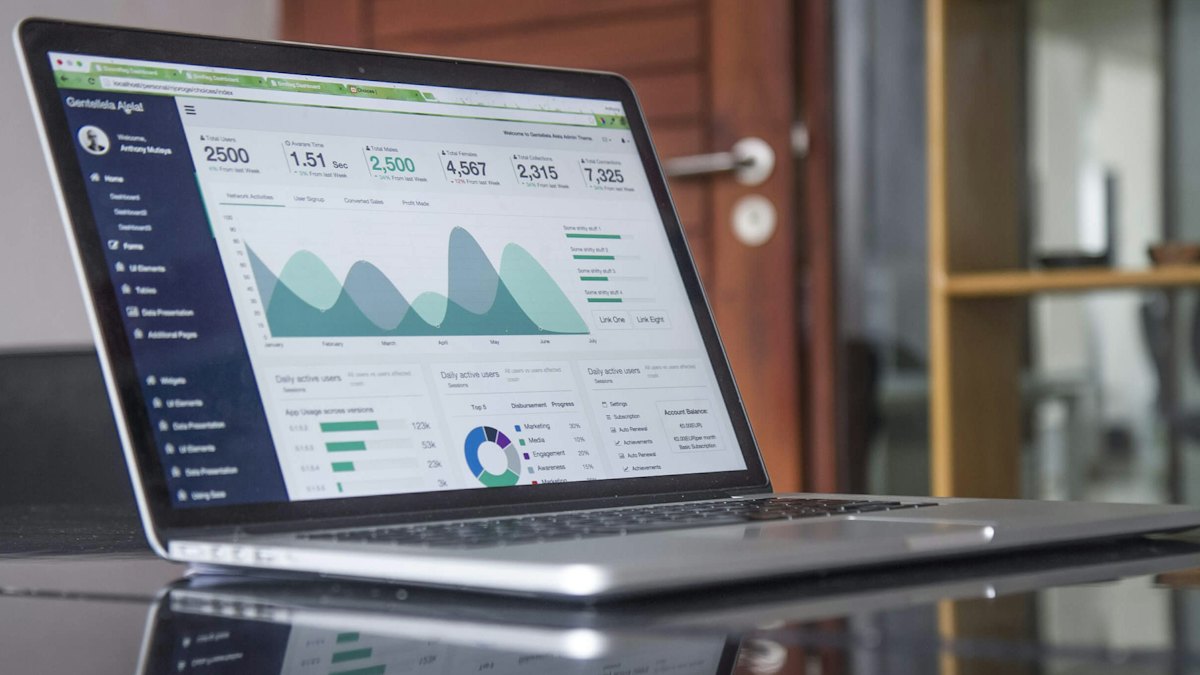 Laptop con un tablero de datos sobre un escritorio de vidrio